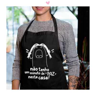 Avental preto com ilustração e texto em branco, usado por pessoa com camisola cinza