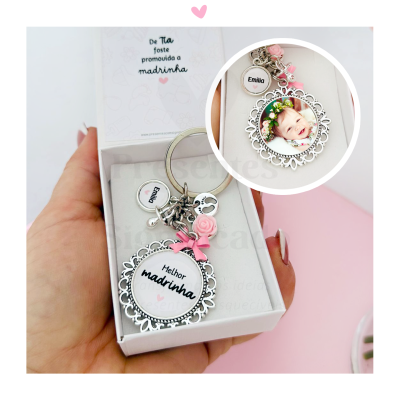 Chaveiro prata com frase 'Melhor madrinha' e detalhes rosa dentro de caixa branca