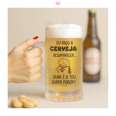 Caneca de vidro com cerveja e texto humorístico, mão a segurar, garrafa e amendoins desfocados ao fundo