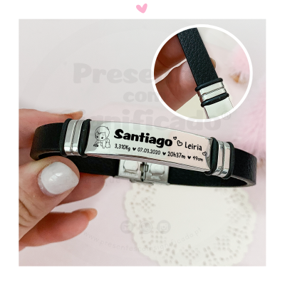 Pulseira preta com placa metálica gravada com dados de nascimento