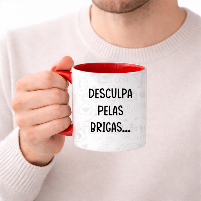 Caneca branca com interior vermelho e texto a preto segurada por uma pessoa.