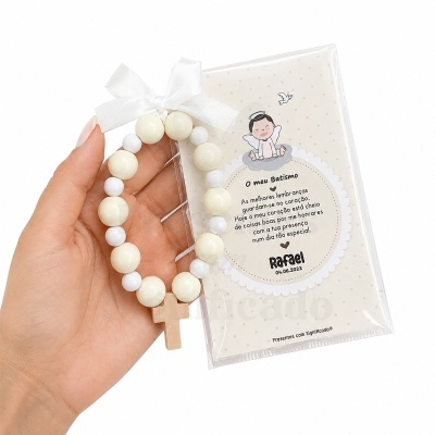 Pulseira branca e creme com cruz de madeira e cartão de lembrança do batismo com texto e ilustração de anjo