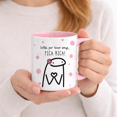 Caneca branca e rosa com texto e desenho decorativo nas mãos de uma pessoa.