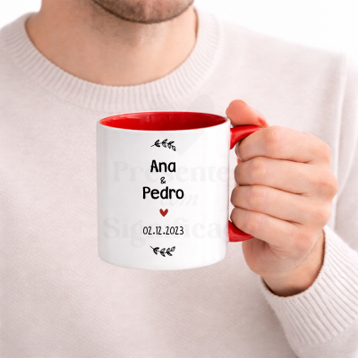 Caneca branca com interior e pega vermelhos e texto personalizado segurada por uma mão