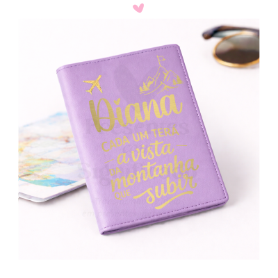 Capa lilás para passaporte com texto dourado e desenhos de avião e montanha, ao lado de óculos e mapa.