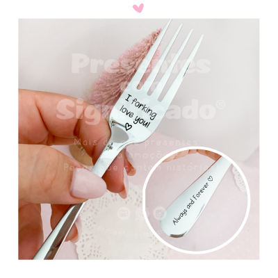 Garfo metálico gravado com frases de amor segurado por mão feminina.