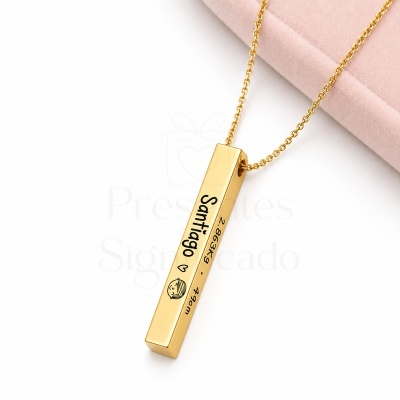 Colar dourado com pendente gravado com nome e medidas em fundo branco.
