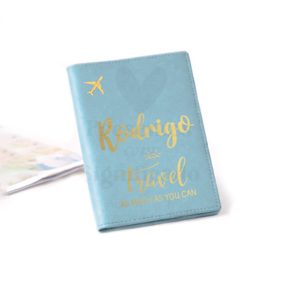 Capa azul clara para passaporte com texto dourado e ícone de avião