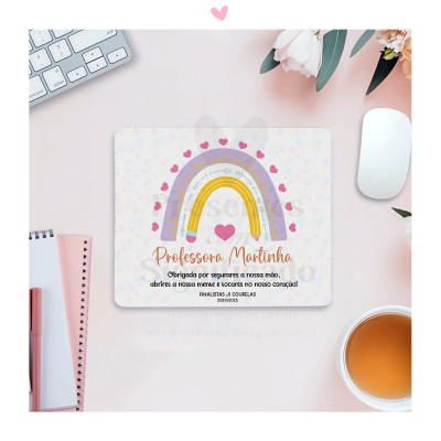 Cartão com arco-íris colorido e texto de agradecimento para professora num ambiente de secretária