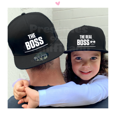 Duas pessoas a utilizar bonés pretos com texto branco, uma criança abraça a pessoa adulta.