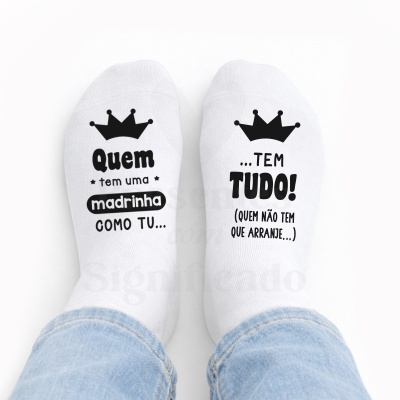 Meias brancas com texto em preto e desenho de coroas, vistas em pés com calças de ganga.