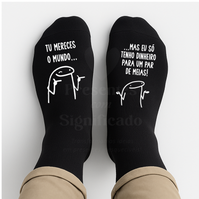 Par de meias pretas com texto humorístico em branco e desenhos, usadas por pessoa com calças bege.