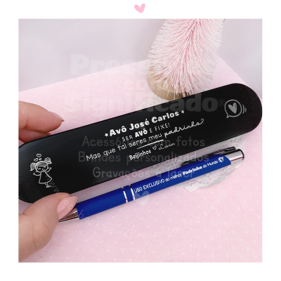 Caneta azul personalizada com estojo preto sobre fundo rosa e escova decorativa