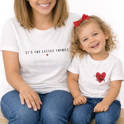 Mãe e filha a usar t-shirts brancas com texto e desenhos em coração, e calças de ganga azuis