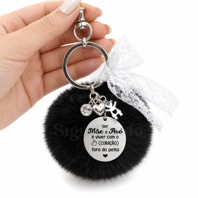 Chaveiro com pompom preto e pendente redondo com texto em português.