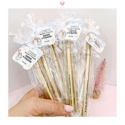 Lápis dourados com etiquetas personalizadas para casamento Daniela e Eduardo 18-06-2022, embalagens transparentes, fundo branco e rosa.