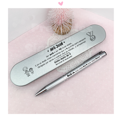 Estojo metálico prateado com caneta gravada dedicada a Avô José sobre fundo rosa com árvore decorativa