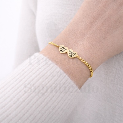 Pulseira dourada com dois corações gravados com nomes, datas e desenhos de rostos