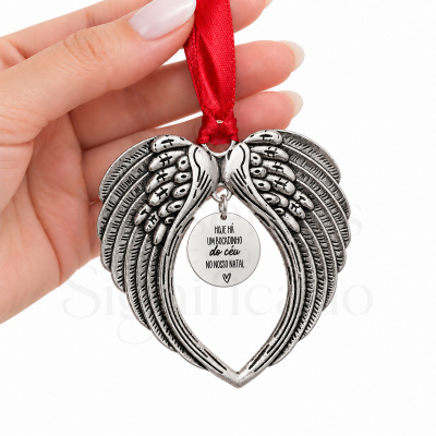 Enfeite de Natal em forma de asas de anjo formando um coração, com texto pendente, em metal prateado e fita vermelha.
