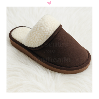 Chinelo castanho com interior branco peludo sobre superfície branca felpuda