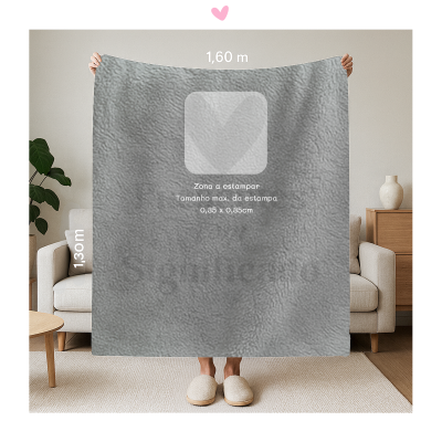 Manta cinza felpuda com dimensões e zona para estampa indicada, segurada em ambiente de sala