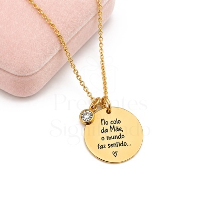 Colar dourado com pendente circular gravado e brilhante sobre superfície branca