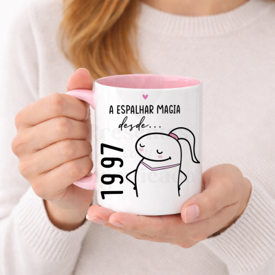 Caneca branca com interior e pega cor-de-rosa com desenho e texto em preto e rosa.