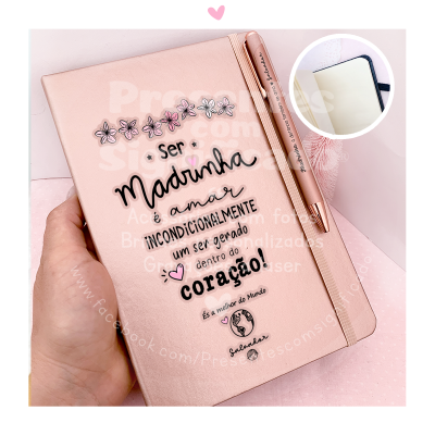Caderno rosa claro com texto decorativo e caneta rosa dourada