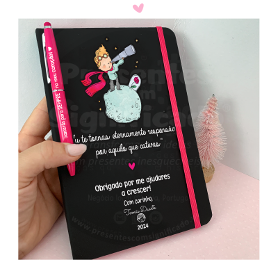 Caderno preto com elástico rosa, ilustração e texto, caneta rosa, mini árvore decorativa