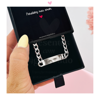 Pulseira prateada numa caixa preta com texto comemorativo
