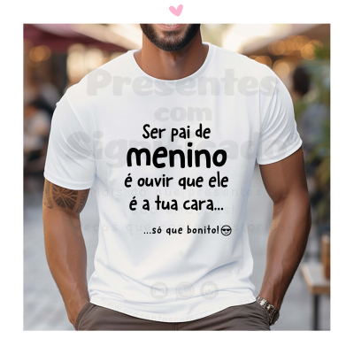 Homem com t-shirt branca com texto em português sobre ser pai de menino, em ambiente urbano desfocado