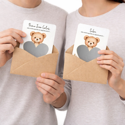 Cartões ilustrados com ursinho e texto em envelopes castanhos nas mãos de duas pessoas com camisolas claras.