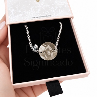 Pulseira prateada com medalhão circular gravado em caixa de joias rosa