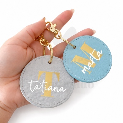 Porta-chaves redondos cinza e azul com letras douradas iniciais e nomes tatiana e marta em branco
