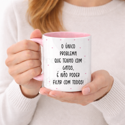 Caneca branca e rosa com texto sobre gatos sendo segurada por uma pessoa com camisola bege claro