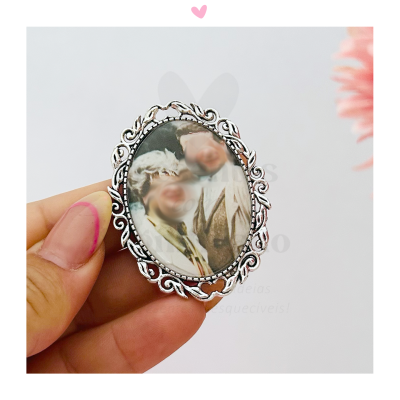 Broche oval prateado com fotografia desfocada de duas pessoas