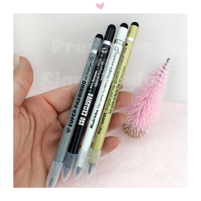 Quatro canetas táteis coloridas seguradas à mão com pinheiro rosa ao fundo