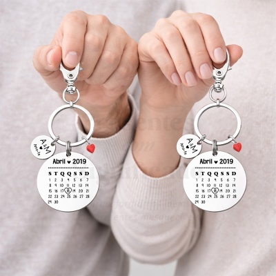 Chaveiros metálicos prateados com calendário gravado e pingentes em formato de coração.
