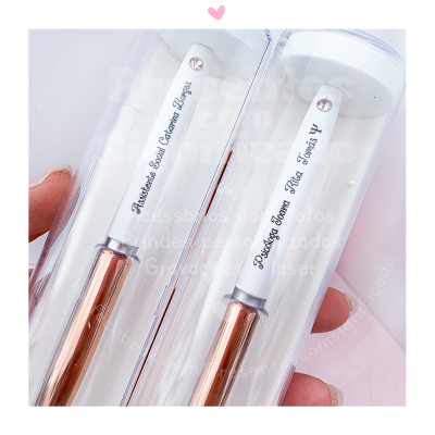 Dois pincéis de maquiagem com cabo branco e dourado em estojo transparente