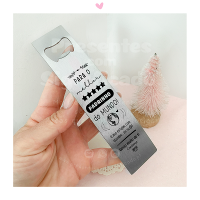Abridor de garrafas metálico com texto para padrinho em fundo rosa com uma árvore decorativa