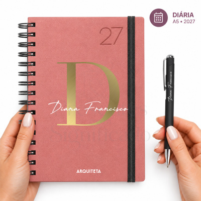 Agenda rosa texturizada com caneta preta personalizada e mãos femininas segurando ambos.
