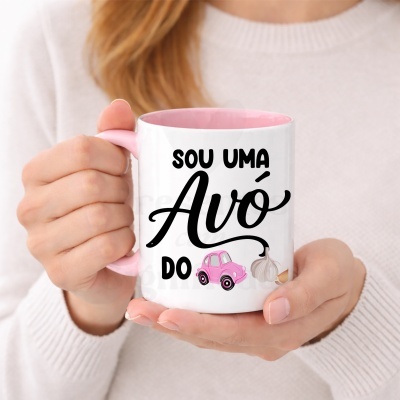 Caneca branca e rosa com texto e ilustrações, segurada por mãos femininas.