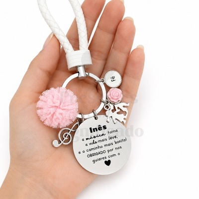 Porta-chaves com pendentes metálicos e pompom rosa em mão