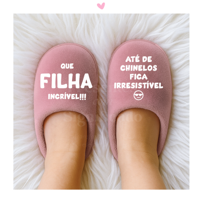 Chinelos de quarto rosa com texto branco e emoji, sobre superfície de pelúcia branca