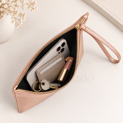Bolsa de mão rosa claro com fecho dourado aberta mostrando conteúdos interiores