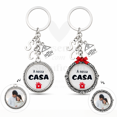 Dois porta-chaves com pendentes casa e texto A nossa CASA em prateado, com fotos de casal no verso.
