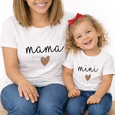 Duas pessoas com t-shirts brancas escritas mama e mini com corações animal print sentadas