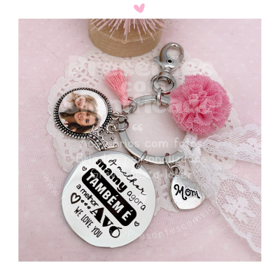 Chaveiro com pendentes metálicos e flor rosa sobre fundo rosa com renda