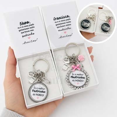 Duas caixas com porta-chaves prateados e mensagens para padrinhos e madrinhas.