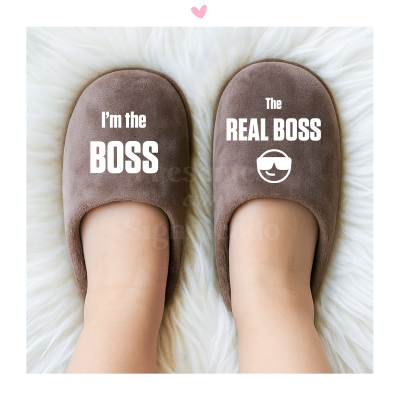 Pantufas castanhas com texto branco 'I'm the BOSS' e 'The REAL BOSS' sobre pele sintética branca.